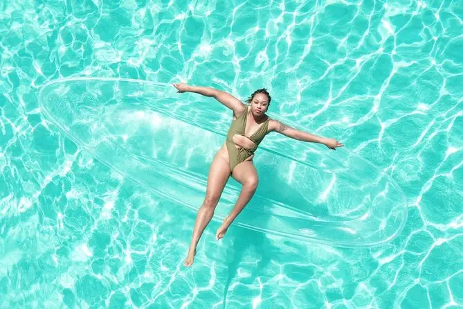 A guest posing with arms outstretched in a clear kayak over turquoise Grand Turk water